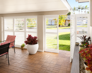 White exterior aluminium shutters enclosing patio area with hinged shutter door