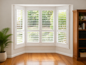 White plantation shutters in bay window wooden floors looking onto garden 